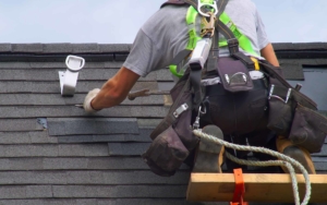 Behind view of a roofing worker installing new shingles
