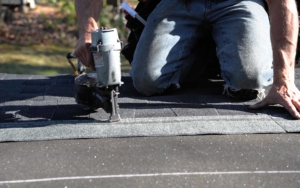 Close up view of a roofer using a nail gun on shingles