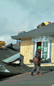 Group of roofing workers installing a new roof on a home vertical