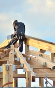 Roof worker on top of the frame of a new building vertical