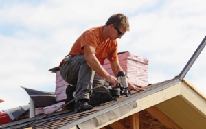 Roofing worker using a nail gun to install shingles