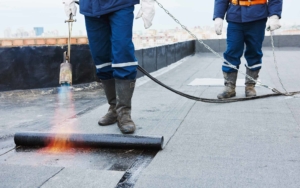 Two roofers using a blowtorch and epdm roll