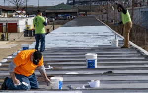 Three roofers repainting a commercial roof