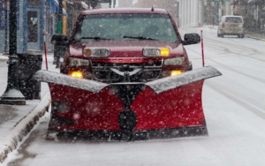 Front view of a red truck with a snow plow during winter