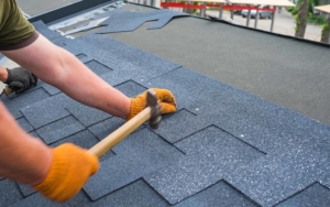 Roofing worker using a hammer to install shingles