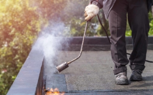 Roofing worker using blow torch to seal EPDM material