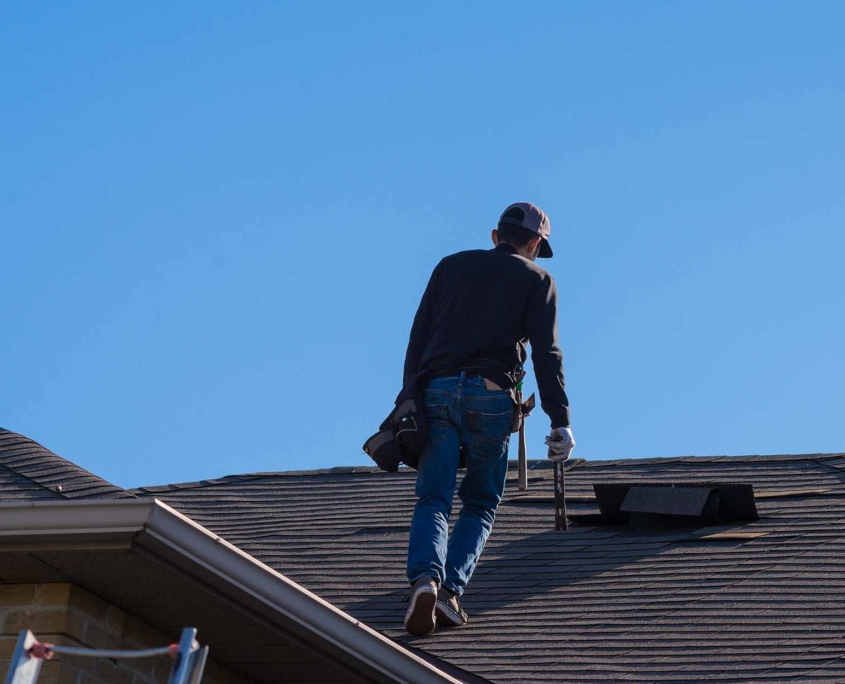 Roofing worker walking up the front of a house