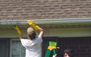 Two workers installing a gutter system on a house