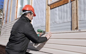Worker installing new siding on the side of a house