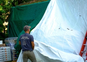 Roofer surrounded by tarps and boxes of shingles