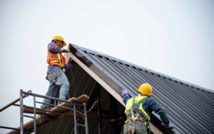 Side view of two roofers installing a metal roof