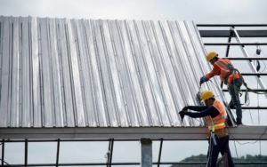 Two roofing workers installing a metal roof