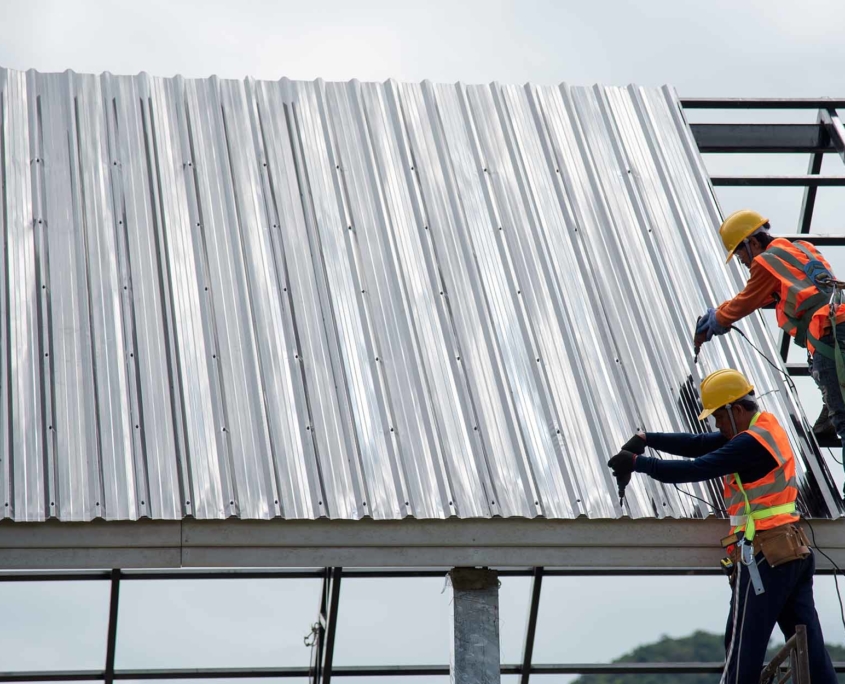 Two roofing workers installing a metal roof