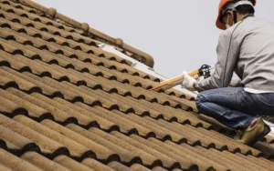 A roofer bent down on top of roof caulking shingles