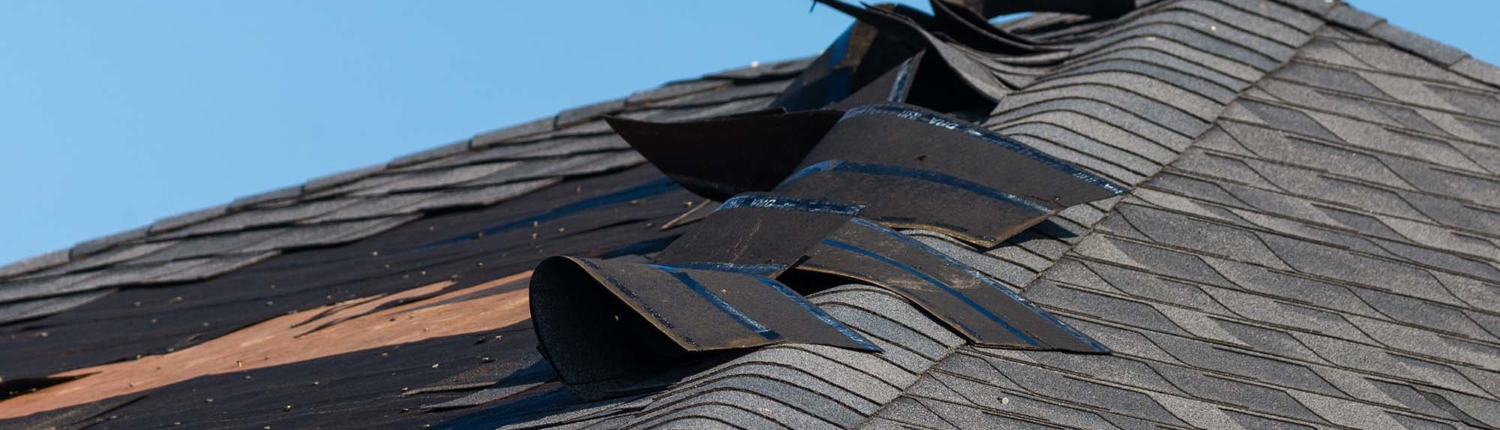 Roof with shingles falling off and sky in the background