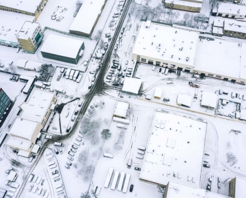 Birds eye view of a snowy office park with lots of cars covered in snow