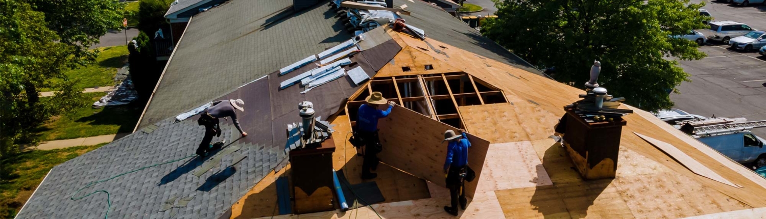 Team of roofers working on top of a roof with tools