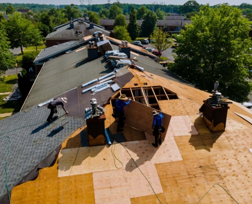 Team of roofers working on top of a roof with tools