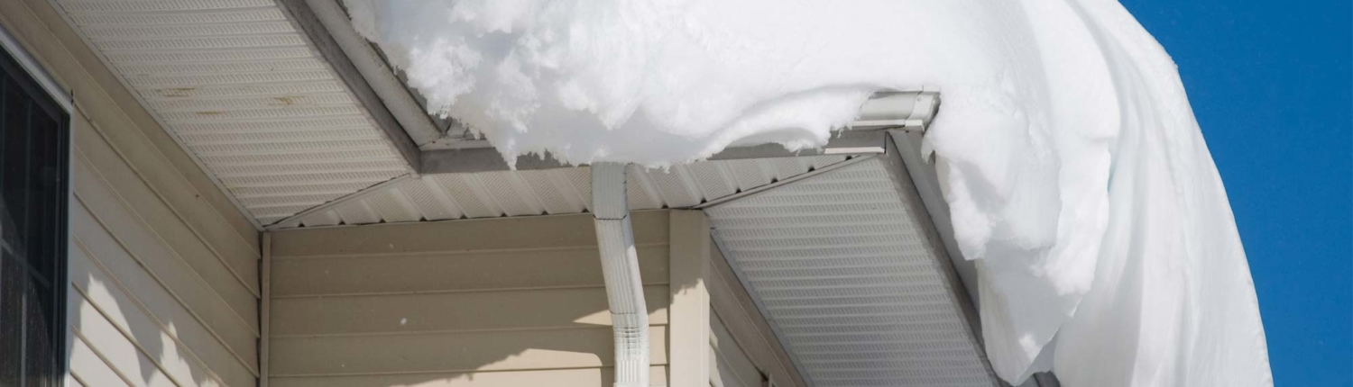 Large heap of snow nearly falling of the edge of roof