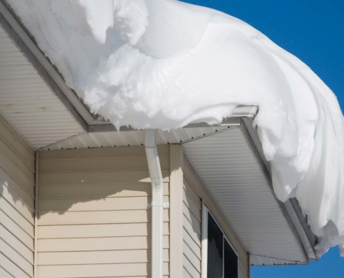 Large heap of snow nearly falling of the edge of roof
