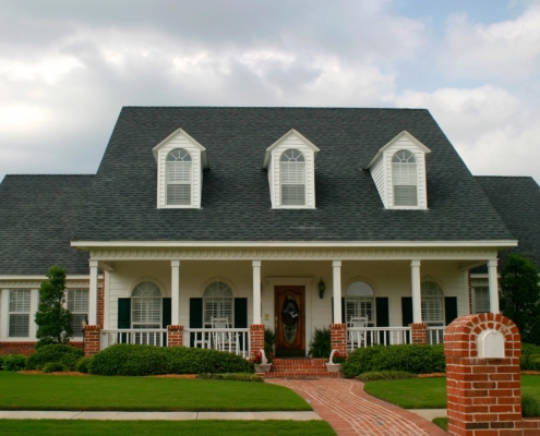 Front view of a brick home with dark gray shingles on roof