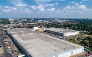 Huge warehouse building with flat roof and cars near city