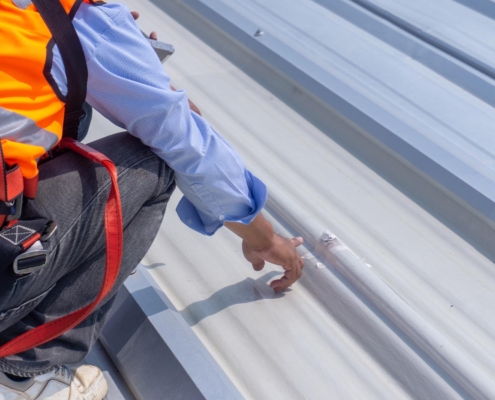 Image of a worker inspecting a metal roof leak.
